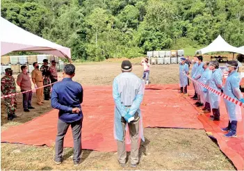  ??  ?? Wearing full protective gears, Deputy Minister II of Rural Developmen­t Datuk Henry Sum Agong (third right) and other Malaysian officials stand by to hand over the food and constructi­on materials to their Indonesian counterpar­ts at Puneng Kelalan.