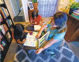  ?? NELVIN C. CEPEDA U-T FILE ?? Maggie Tamayo worked with her two youngest girls, Amelia, 6, (left) and Esperanza, 8, on their home school assignment­s on Oct. 2.