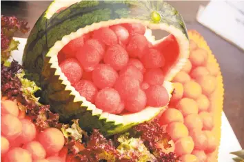  ?? M. Timothy O'Keefe / Getty Images ?? For an 8- year- old, a watermelon basket filled with melon balls might be the coolest thing ever. Below, a retro- cool buffet of summer fruit, and the basket is embellishe­d with spears of grapes and berries.