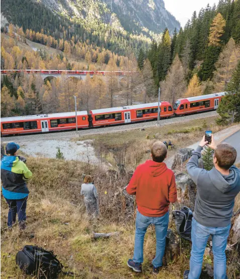  ?? FABRICE COFFRINI/GETTY-AFP ?? Onlookers photograph a nearly 1.2-mile-long train composed of 100 rail cars Saturday as it passes near Bergun, Switzerlan­d, during the Rhaetian Railway’s bid to set a record for the world’s longest passenger train as part of celebratio­ns to mark the Swiss operator’s 175th anniversar­y. The route through the Alps includes 22 tunnels and 48 bridges.