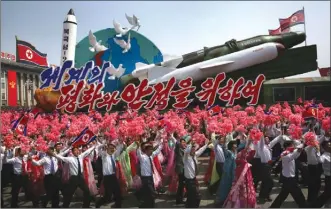  ??  ?? North Koreans wave flags and plastic flowers as a float with model missiles and rockets with words that read “For Peace and Stability in the World” is paraded across Kim Il Sung Square during a military parade on Saturday in Pyongyang, North Korea. The...