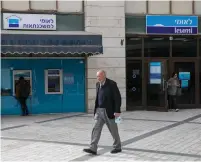  ??  ?? A CUSTOMER exits a Bank Leumi branch in central Jerusalem. (Olivier Fitoussi/Flash90)