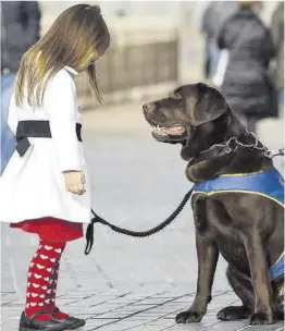  ?? Javier Etxezarret­a ?? Una niña con autismo, con su perro de asistencia, en el País Vasco.