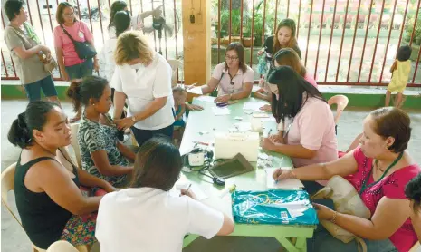  ?? (SUN.STAR FOTO/ALLAN DEFENSOR) ?? MEDICAL CHECKUP. Cebu City Health doctors check on the health of victims of the Duljo-Fatima fire who are now staying at the San Nicolas Elementary School. Some 200 of them fell ill, reports say.