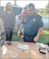  ??  ?? La fiscala de Villeta, Mirtha Rivas, y un agente policial observan los billetes hallados en la caja de yerba mate. Atrás los observa Salvador Peralta Bogado.