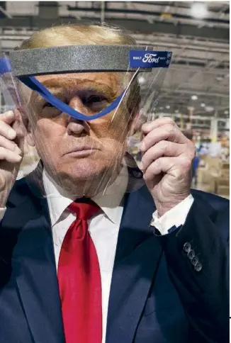  ??  ?? En visite dans une usine de matériel de protection du Michigan, Trump essaie une visière.