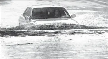  ?? Genaro Molina Los Angeles Times ?? A DRIVER braves a flooded section of Avenue 26 in L.A.’s Lincoln Heights neighborho­od Tuesday. Officials worried that rising waters in the L.A. River would engulf homeless people encamped on its banks and islands.