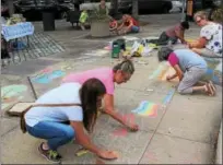  ?? MICHILEA PATTERSON — DIGITAL FIRST MEDIA ?? People color in a sidewalk sketch of a town with chalk during the Sidewalk Chalk Festival at Smith Family Plaza on Thursday. The festival was part of the “Almost Friday” event of the weekly outdoor farmers market in Pottstown.