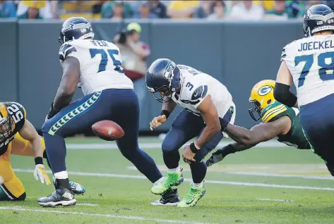  ?? JOE ROBBINS/GETTY IMAGES ?? Seattle Seahawks quarterbac­k Russell Wilson fumbles the football as he is hit by Green Bay Packers defensive lineman Mike Daniels in the third quarter on Sunday in Green Bay, Wis. Wilson’s offence couldn’t manage a touchdown as the Packers won 17-9.