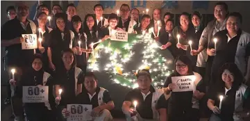  ??  ?? Employees of Interhill Group gather at the office lobby to celebrate Earth Hour.