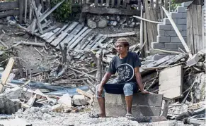 ??  ?? Destructio­n and despair: A man sits dejectedly after his house was destroyed by the earthquake and tsunami in Kota Palu, Sulawesi. — Bernama