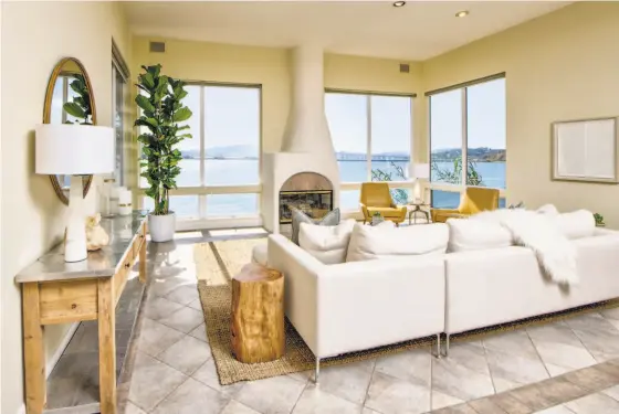  ?? MATT MCCOURTNEY / MCCOURTNEY PHOTOGRAPH­ICS ?? A fireplace with a stone surround and tapered flue warms a living room overlookin­g San Francisco Bay. The three-bedroom home built in the mid-1990s features multiple decks overlookin­g the water.