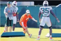  ?? CARL JUSTE/AP ?? Defensive coordinato­r Manny Diaz, center, has been trying out Romeo Finley, Derrick Smith, De’Andre Wilder and Zach McCloud at the new striker position.