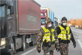  ?? Mindaugas Kulbis / Associated Press ?? Lithuanian border guards walk along trucks stuck in traffic for 37 miles after Poland closed its border, while similar jams could be seen on the borders with Germany and Czech Republic.