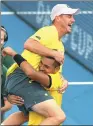  ?? STEVE HOLLAND / REUTERS ?? Nick Kyrgios lifts team captain Lleyton Hewitt into the air after beating Sam Querrey of the US to earn Australia a Davis Cup quarterfin­al win on Sunday.