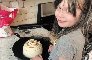  ?? WHITNEY RUTZ ?? Elsa Rutz poses with a cinnamon roll baked by her mom, Whitney, at their home in Portland, Ore. The vast majority of cinnamon rolls made by Whitney have been donated to health-care workers.