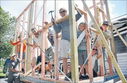  ??  ?? Happy builders: D’Arcy Lunn, centre, and volunteers build a house on the back of a boat trailer in Paekakarik­i.