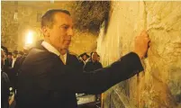  ?? (Western Wall Rabbi’s Office) ?? AUSTRIAN CHANCELLOR Christian Kern places a note in the Western Wall on Monday night.