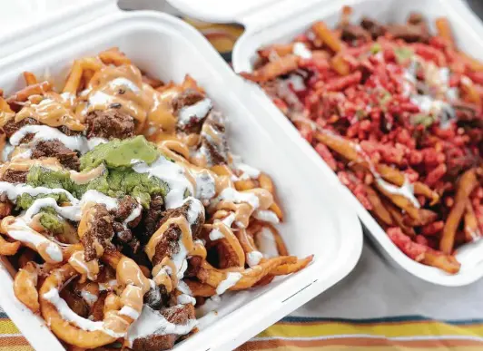  ?? Paul Stephen / Staff ?? Heavily seasoned NorCal Asada Fries, left, are topped with steak, guacamole, sour cream and “secret sauce.” The SorCal has similar toppings, plus Flamin’ Hot Cheetos.