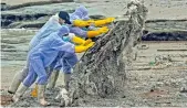  ?? AFP ?? Sri Lankan Navy soldiers work to remove debris washed ashore from the Singapore-registered container ship MV X-Press Pearl, which has been burning for the ninth consecutiv­e day, in Colombo on Friday. —