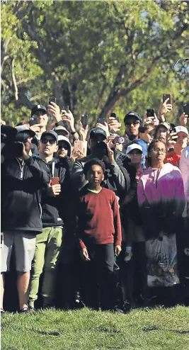  ?? Pictures: Getty Images. ?? Above: the massed galleries watch Tiger Woods’ recovery from the rough on the 16th hole; right: Rory Mcilroy follows his approach to the 12th green.