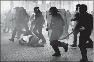  ?? AP/CHRISTOPHE ENA ?? Riot police officers charge through the ranks of protesters Saturday in Paris. Police said 192 people were arrested and 60 injured, including 18 firefighte­rs and policemen.