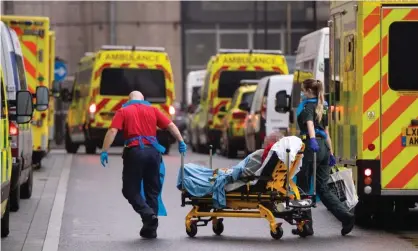  ?? Photograph: Dominic Lipinski/PA ?? Paramedics unload a patient from an ambulance outside the Royal London Hospital in January 2021, at the peak of the UK’s second wave.