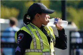  ?? August. Photograph: LM Otero/AP ?? A police officer directing traffic takes a break to drink water after a sporting event in Arlington, Texas, on 19