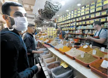  ?? TOUFIK DOUDOU/AP ?? With Ramadan on the horizon, a customer wearing a face mask shops at a market Tuesday in Algiers, Algeria.