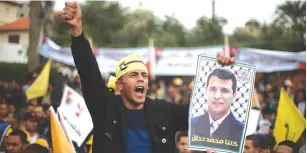  ?? ( Mohammed Salem/ Reuters) ?? A SUPPORTER of Mohammed Dahlan holds a poster depicting the exiled politician during a protest in Gaza City against Palestinia­n Authority President Mahmoud Abbas.