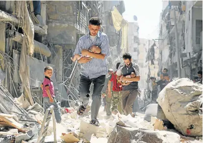  ?? Picture: AFP ?? MOST VULNERABLE: Men carry infants as they make their way through the rubble following air strikes on Aleppo