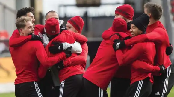  ?? NATHAN DENNETTE/THE CANADIAN PRESS ?? Toronto FC teammates share the warmth during Friday’s final practice ahead of Saturday’s big game at BMO Field. Last year’s chilly showdown against the Seattle Sounders went to a shootout.