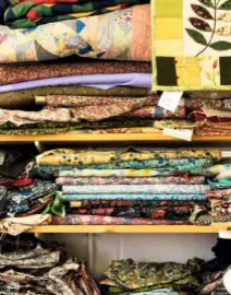  ??  ?? Bolts of fabric piled high on the shelves. Often they are highly patterned, adding to the detail within the appliqués and panels of the quilts.