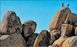  ?? MARIO TAMA/GETTY ?? Rock climbers stand Friday on top of a formation at Joshua Tree National Park, which has remained open during the shutdown. Campground­s at the California park have closed.