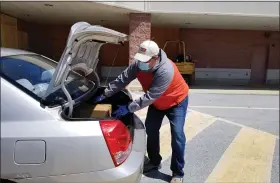  ?? MICHELLE N. LYNCH — MEDIANEWS GROUP ?? Volunteer Jack Williams of Exeter Township loads a trunk Wednesday during the Exeter Area Food Pantry’s third drive-by grocery giveaway.