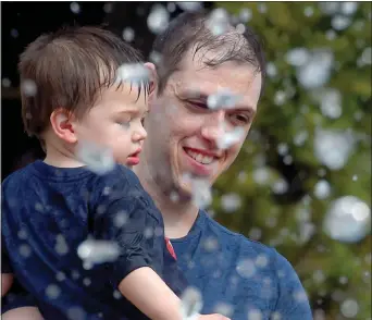  ?? JIM MICHAUD/ BOSTON HERALD ?? Ken Herbison of Fitchburg cools off with his son Eric, 2, at the Rings Fountain on the Rose Kennedy Greenway, Sunday on Atlantic Avenue in Boston.