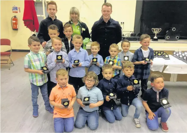  ??  ?? AFC Llwydcoed U7s players receive their trophies from special guest Julie Cook, of Asda Aberdare Foundation, accompanie­d by u7s coaches Connor Waters and Connor Williams
