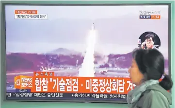  ??  ?? A woman walks past a television screen showing file footage of a North Korean missile launch, at a railway station in Seoul. — AFP photo