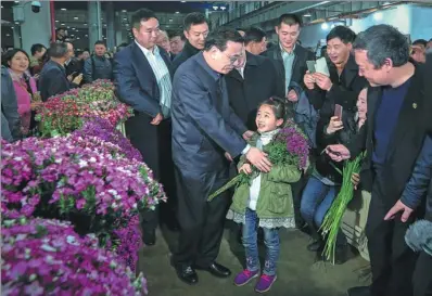  ?? WU ZHIYI / CHINA DAILY ?? Premier Li Keqiang greets a girl during a visit to a flower market in Kunming, Yunnan province, on Tuesday. Li, who bought two bouquets, told the florists, “You wake up early and go to bed late, and your hard work brings happiness to the people. I wish...