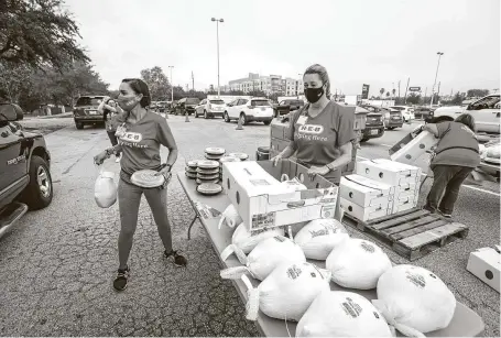  ?? Photos by Steve Gonzales / Staff photograph­er ?? H-E-B’s Lacey Dalcouk Salas and Julie Lambert deliver pies and turkeys to waiting vehicles during the H-E-B Family Thanksgivi­ng Distributi­on on Saturday at NRG Stadium.