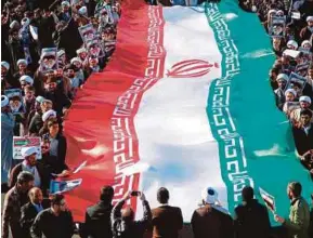  ?? AFP PIC ?? Pro-government demonstrat­ors waving the national flag during a march in Iran’s holy city of Qom recently as tens of thousands gathered across the country to support the rulers after days of unrest.