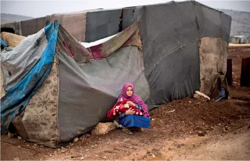  ?? ?? A Syrian woman
Holds A BABY In A REFUGEE Camp For DISPLACED people supported By THE Turkish RED Crescent In SARMADA District, north of IDLIB City, SYRIA.— ap