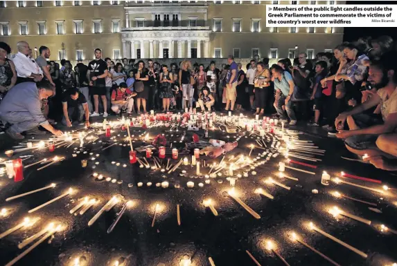  ?? Milos Bicanski ?? > Members of the public light candles outside the Greek Parliament to commemorat­e the victims of the country’s worst ever wildfires