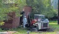  ?? JORDAN SMITH ?? A worker wearing personal protective equipment cleans out an old brick building at the Drewrys Brewery complex at 1408 Elwood Ave. Work to remove asbestos from the site began this month.