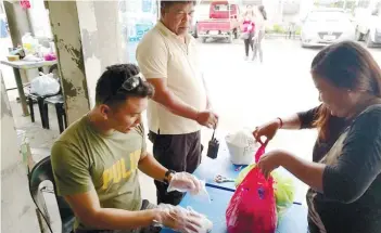  ?? SUNSTAR FOTO / ALLAN CUIZON ?? INSPECTION. A policeman assigned in the Cebu Provincial Detention and Rehabilita­tion Center checks the items brought by a visitor of an inmate at the entrance of the facility.