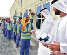  ?? Courtesy: SLSDA ?? Officials from the Sharjah Labour Standards Developmen­t Authority distributi­ng the special summer jackets to workers in the area surroundin­g the University of Sharjah campus.