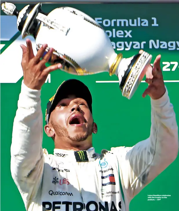  ?? AFP ?? Leiws Hamilton celebrates with the trophy on the podium. —