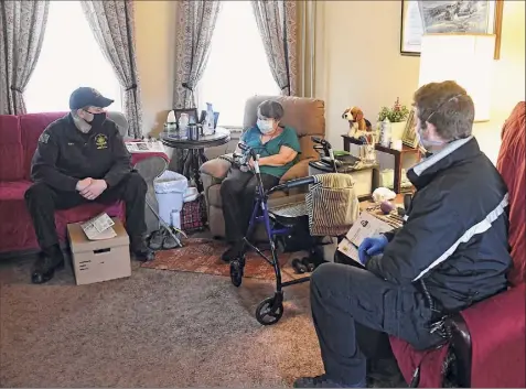  ?? Lori Van Buren / Times Union ?? EMTS and Paramedics James Mudge, left, and David Gallati talk with Ruth Munro after administer­ing her second dose of the vaccine on Friday in her Albany home. Gallati and Mudge work in the EMS division of the Albany County Sheriff’s Office.