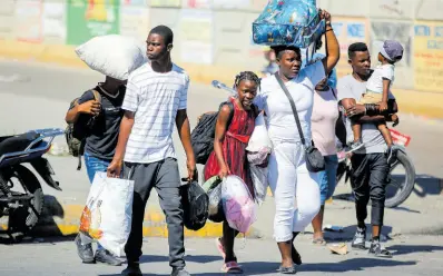  ?? APV ?? Residents of the Solino neighbourh­ood, who were displaced from their homes due to clashes between armed gangs, seek shelter as they walk along a street in the Carrefour community of Port-au-Prince, Haiti on Thursday.