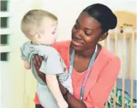  ??  ?? Shauntel Walters shares a moment with an orphan child.